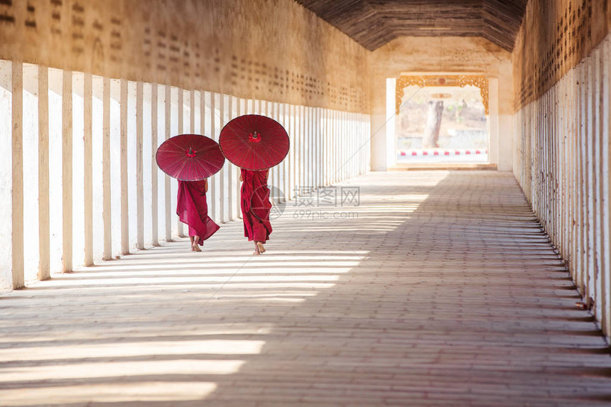 缅甸巴甘市寺庙内带红色雨伞行图片