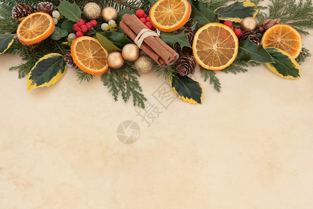 圣诞节背景与橙色水果肉桂棒金小玩意冬青槲寄生和冬季绿色植物在羊皮图片