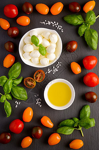 黑底的意大利菜食料莫扎里拉西红柿巴西尔和橄榄图片