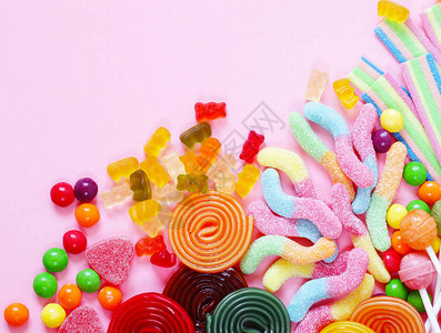 粉红色背景中的彩色糖果和冻糖果图片
