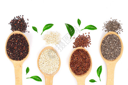 黑红白藜麦和奇亚籽在木勺上装饰着绿叶背景图片