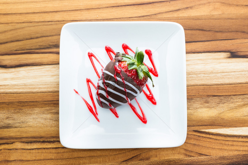 白盘上覆盖着巧克力的草莓图片