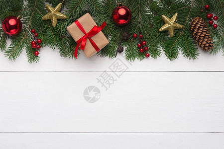圣诞装饰品白色木质背景上带红球金星和礼盒的绿色杉木顶视图片
