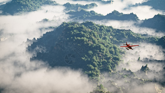 红色飞机越山峦云中松树空中拍摄图片