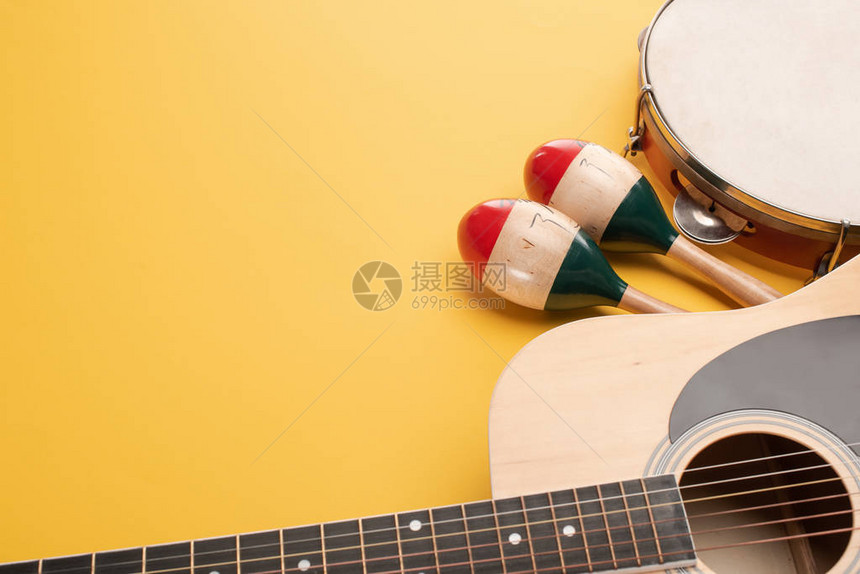 黄色背景上带有手鼓和原声吉他的木制彩色马拉卡斯图片
