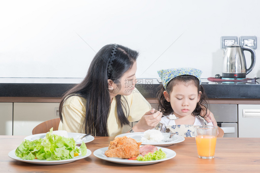亚裔女孩对母亲喂饭时吃大米表示厌恶而图片