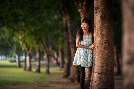 站在公园树旁的亚洲小女孩背景图片