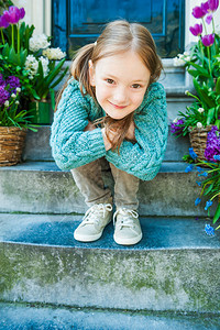 一个可爱小女孩的户外肖像坐在城市的台阶上背景图片