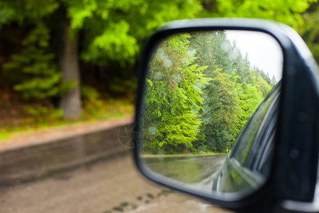 一辆汽车侧视镜面子中的湿路和夏图片