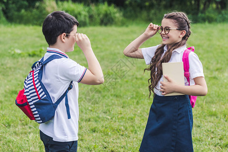 带着背包的可爱学童透过眼镜互相看望对方图片