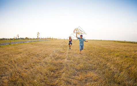 在夏日田野上玩放风筝的快乐小孩图片