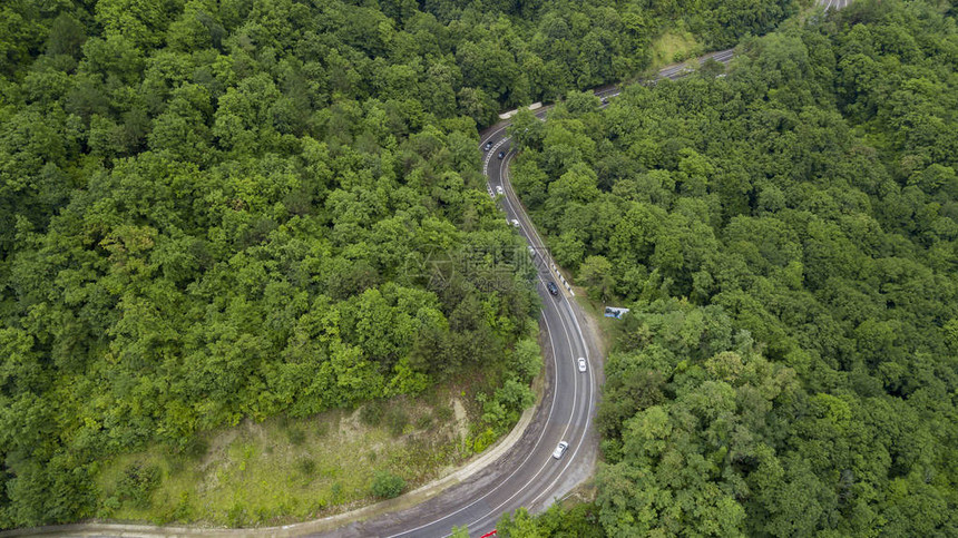 汽车沿着蜿蜒的山口公路穿过俄罗斯索契森林的空中库存照片图片