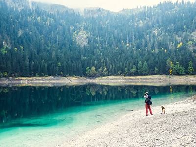 带狗的年轻人在湖边散步图片