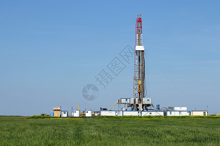绿色麦田上的陆地石油钻机背景图片