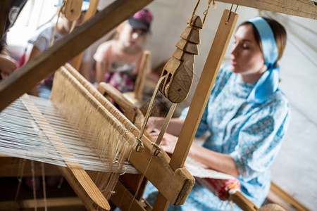 这名妇女正在俄罗斯当地村庄使用木质织布来编织多彩图片
