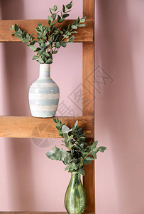 木梯上有绿色桉树枝的花瓶图片