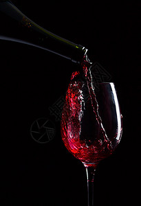 黑色背景上的红酒瓶和玻璃杯图片