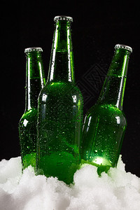 深色背景下雪中的啤酒瓶背景图片