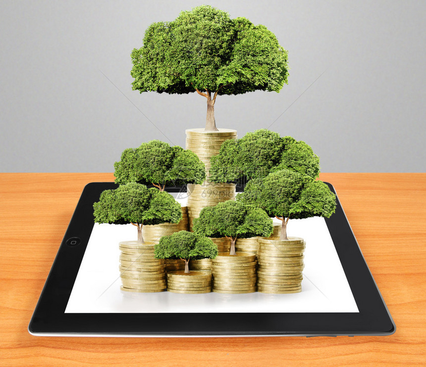 平板电脑秀金钱树从金钱中生长的概念图片