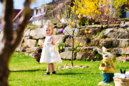 在春天在草地上狩猎复活节的小女孩她拿着篮子图片