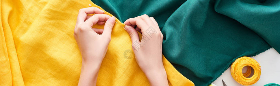 用白底针头缝制彩色布料的裁缝者拍图片