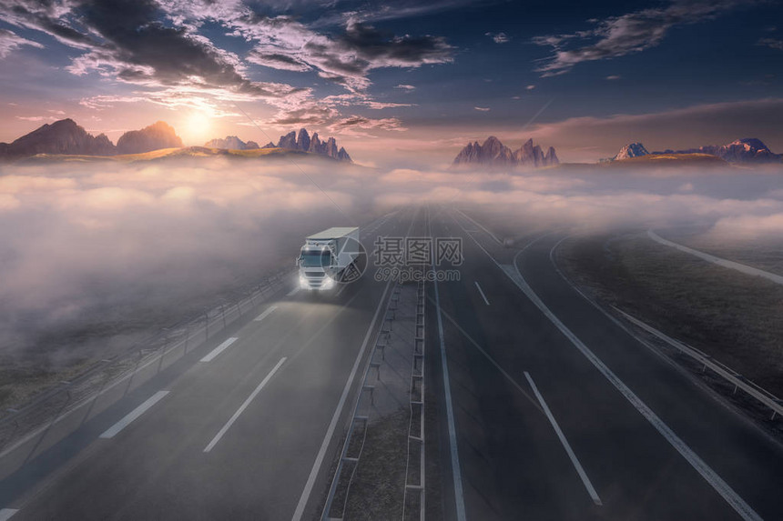 送货卡车在美丽的日出中驶向山脉图片