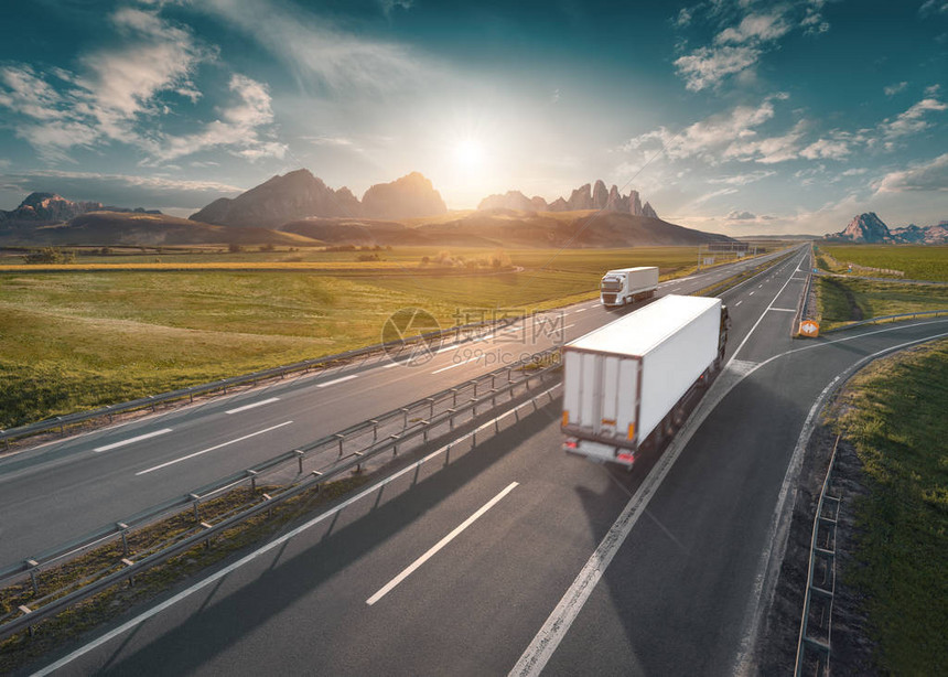 送货卡车在美丽的日出中驶向山脉在美丽的风景中笔直的高速公路上快速模糊的运动驱器高速公路图片