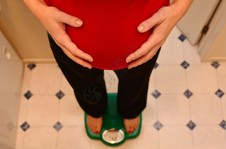 孕妇在怀孕期间站在比例上妊娠孕妇生活方式和保健的概念照片复本室图片