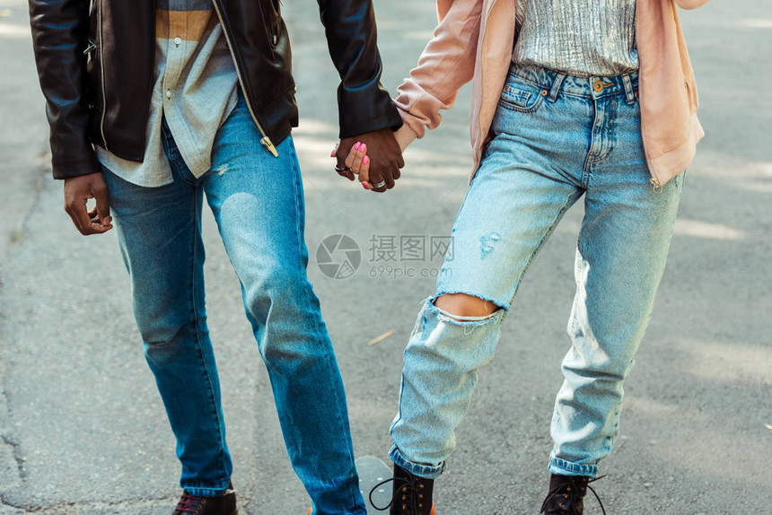 穿着时装鞋和牛仔裤的夫妇在长板上站在一起并握图片
