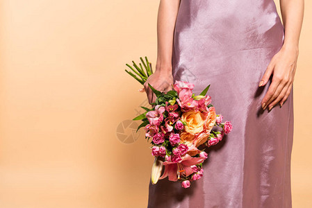穿着紫罗兰花边裙的优雅女人部分地看见她拿着在米色背景图片
