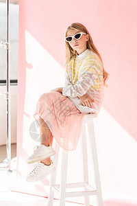 坐在粉红色的凳子上的太阳眼镜上时髦的图片