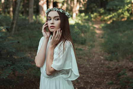 穿着白裙子和森林花环的美丽年轻女孩背景图片