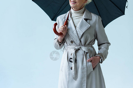 灰色隔离的挂着雨伞的海沟大衣中高级女背景图片