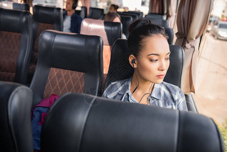 乘公车旅行时用耳听器收听音乐的美丽的背景图片