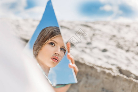 迷人的女孩拿着一面镜子仰图片
