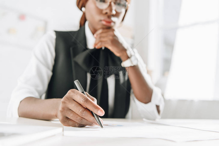 使用笔戴眼镜并从事办公室文件工作的非洲成年女建筑师有选择地重点选用图片