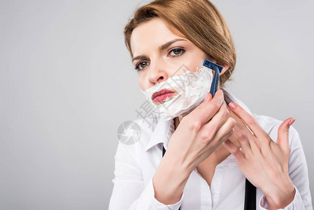 女商人用剃刀刮发泡沫孤立在灰色女图片