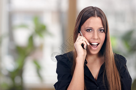 兴奋的女商人通过电话交谈图片