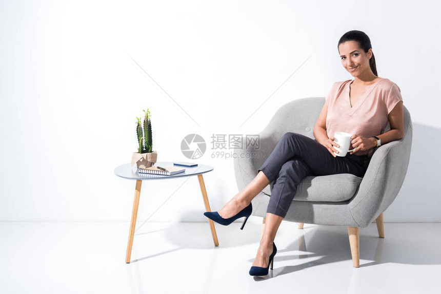 微笑着的女商人在坐椅子上与白隔绝时图片