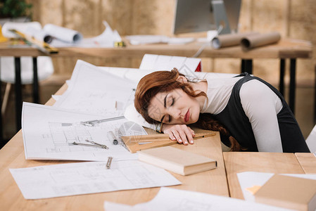 过度劳累的女建筑师睡在工作场图片