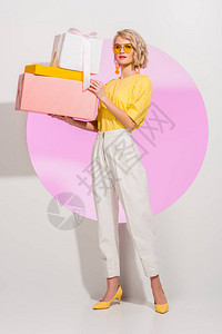 美丽的时装美女拿着礼物盒看着有粉色圆圈背景图片