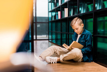 男孩看书坐在图书馆的地板上图片