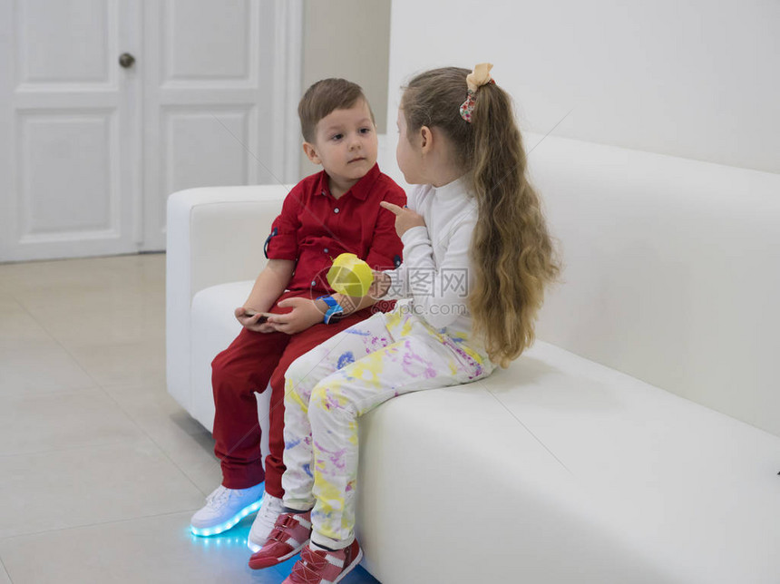 小男孩和女孩坐在沙发上聊天女孩拿着青苹果男孩穿着发光的l图片