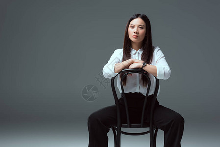 美丽的亚洲女孩坐在椅子上看着背景图片