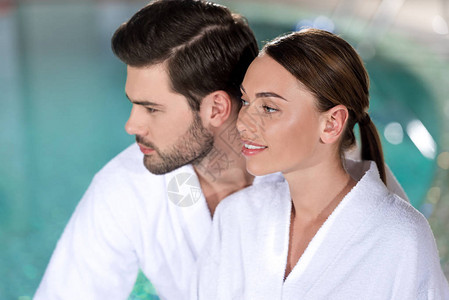 穿着浴袍微笑的年轻夫妇在温泉图片
