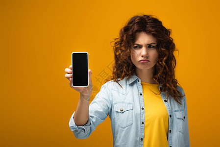 心烦意乱的女人拿着智能手机橙背景图片