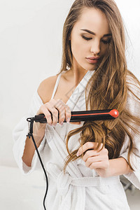 女人用直发器拉直头发的肖像图片