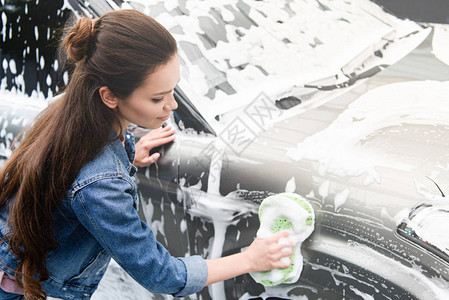 在洗车时用抹布和泡沫洗车的有吸引力的妇女图片