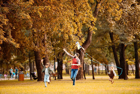 父亲和两个孩子跑过秋天公图片