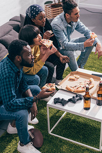 多种族朋友吃披萨和看美式足球比赛的高角度视角图片